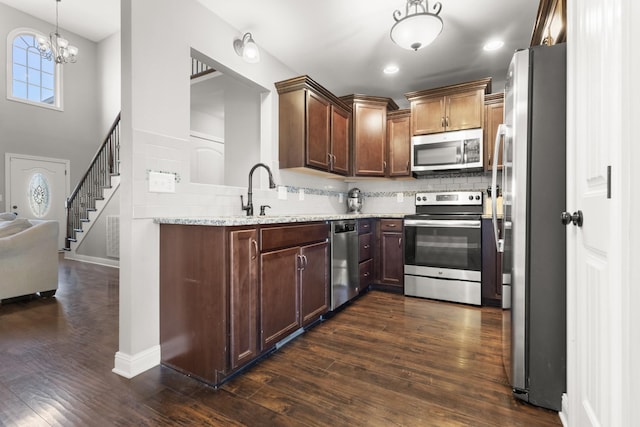 kitchen featuring decorative light fixtures, dark wood finished floors, decorative backsplash, appliances with stainless steel finishes, and open floor plan