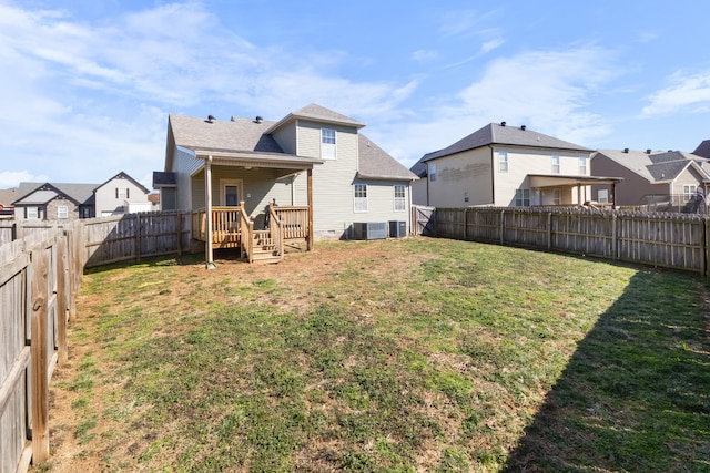 back of house featuring a residential view, a fenced backyard, a lawn, and central AC