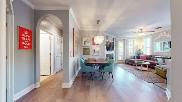 dining space with baseboards, crown molding, visible vents, and light wood finished floors