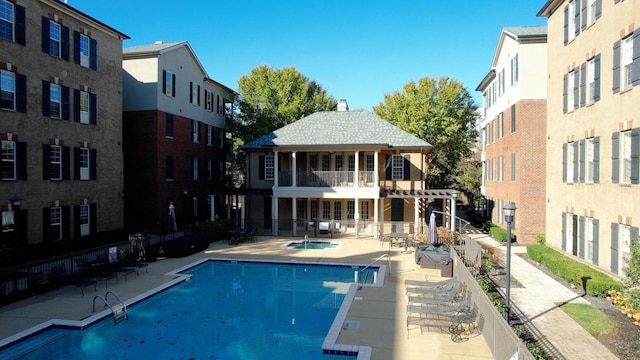 pool with a community hot tub, a patio area, fence, and a pergola