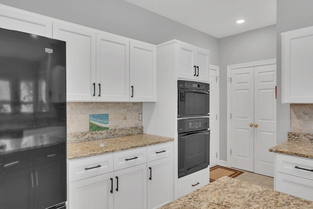 kitchen featuring white cabinets, backsplash, black appliances, and light tile patterned floors