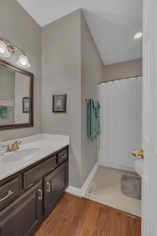 bathroom with visible vents, toilet, vanity, wood finished floors, and baseboards