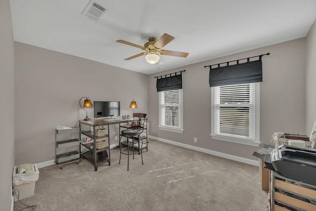 home office with visible vents, ceiling fan, light carpet, and baseboards