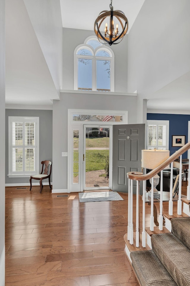 foyer with a chandelier, a high ceiling, wood finished floors, baseboards, and stairway