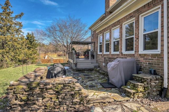 view of home's exterior with brick siding, a chimney, fence, and a gazebo