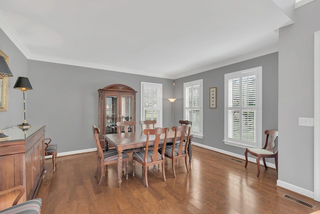 dining space with crown molding, visible vents, dark wood finished floors, and baseboards