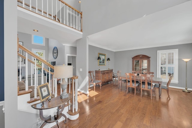 interior space featuring stairs, a high ceiling, wood finished floors, and baseboards