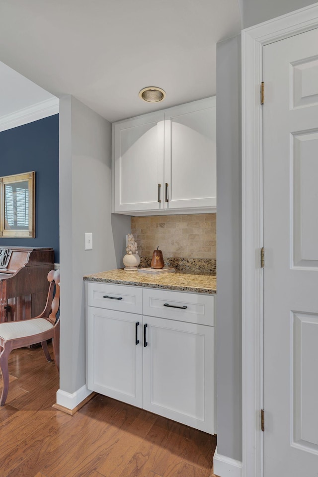 bar featuring light wood-type flooring, baseboards, backsplash, and ornamental molding