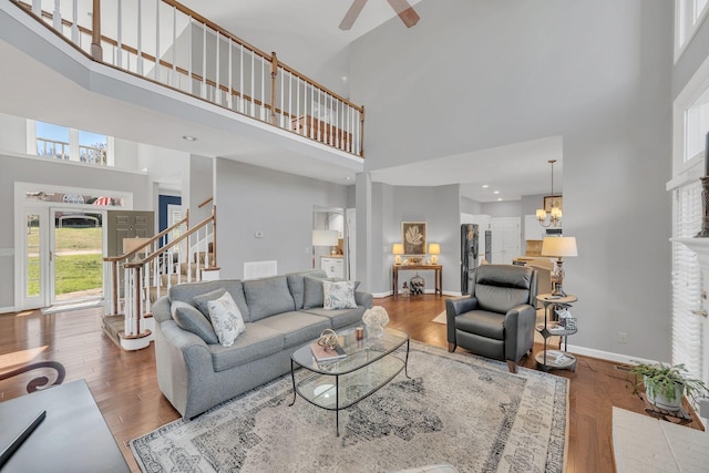 living area featuring stairs, wood finished floors, a towering ceiling, and baseboards