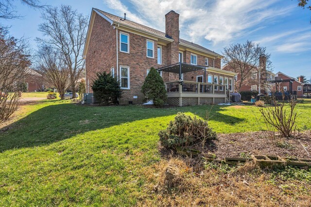 back of property with a sunroom, a chimney, a lawn, and brick siding