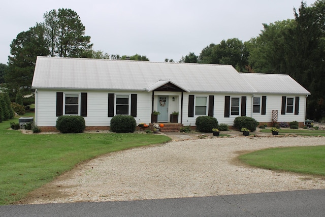 ranch-style house with driveway, metal roof, and a front lawn