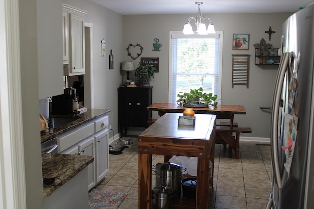 dining space with light tile patterned floors, baseboards, and a chandelier