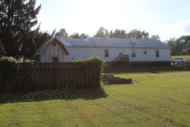 rear view of property featuring a lawn and fence