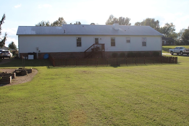 rear view of property with metal roof, a yard, and fence