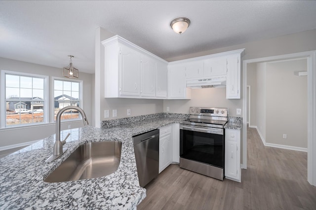 kitchen with white cabinets, light wood-style flooring, stainless steel appliances, under cabinet range hood, and a sink