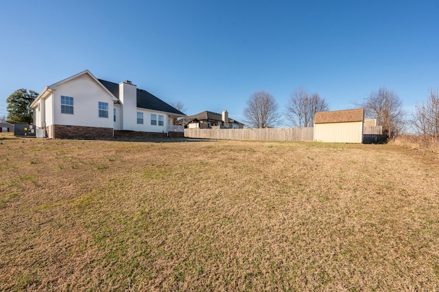 view of yard with fence, a storage unit, and an outdoor structure