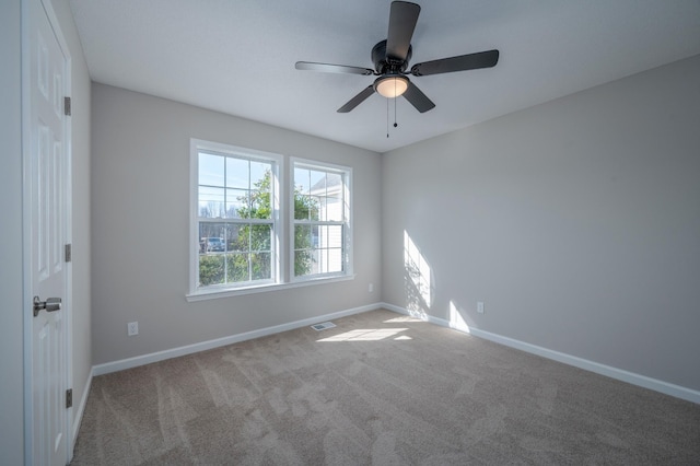 carpeted empty room with a ceiling fan, visible vents, and baseboards