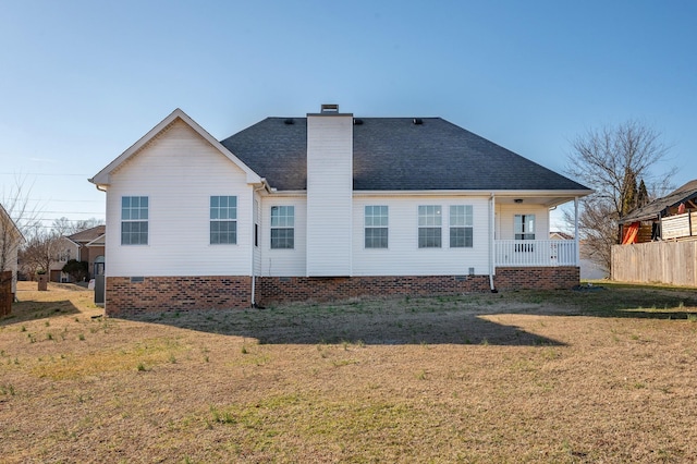 back of house featuring a yard, a chimney, a shingled roof, covered porch, and crawl space