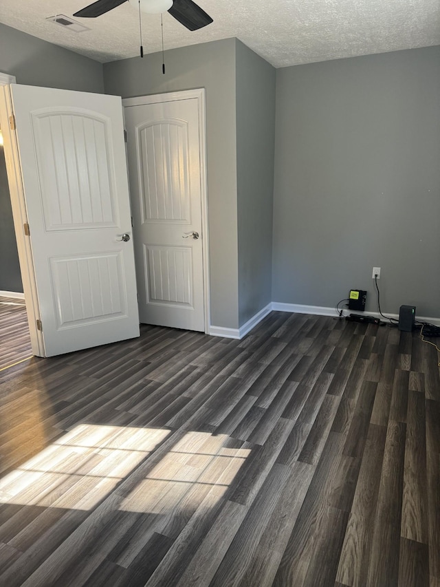 unfurnished bedroom with visible vents, a ceiling fan, a textured ceiling, dark wood finished floors, and baseboards