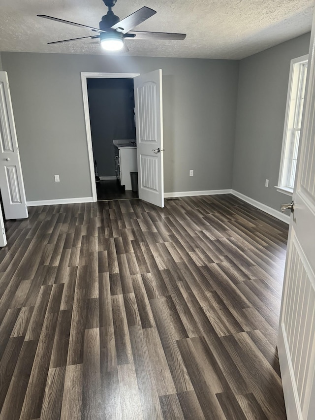unfurnished bedroom featuring baseboards, a textured ceiling, and dark wood finished floors