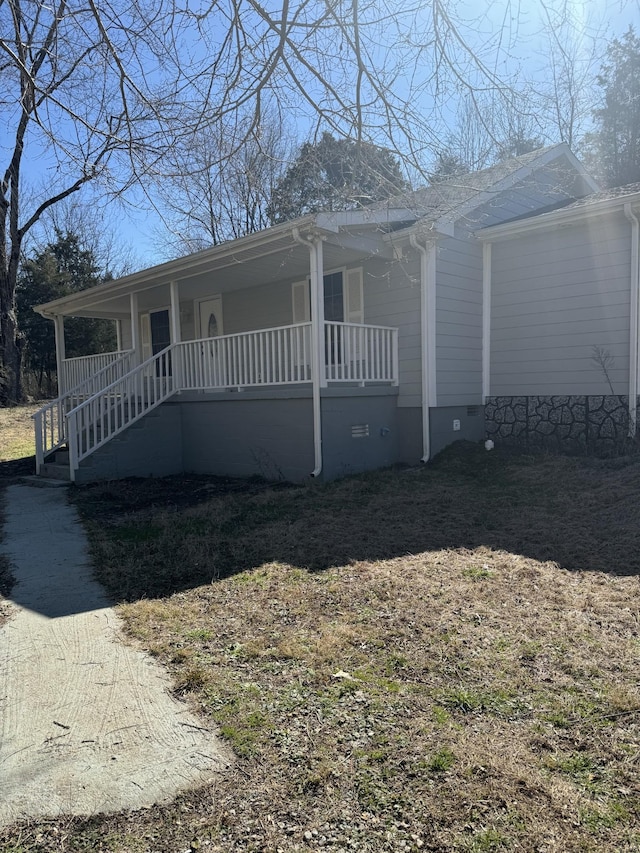 view of front of property featuring crawl space, covered porch, and stairway