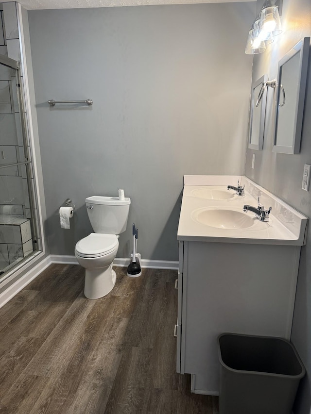 full bathroom featuring vanity, wood finished floors, baseboards, a stall shower, and toilet