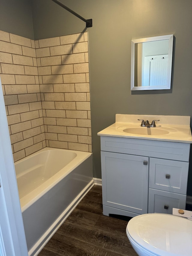 full bath with bathing tub / shower combination, wood finished floors, vanity, and toilet