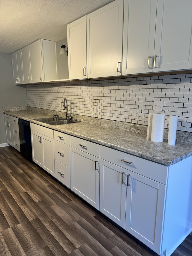 kitchen with dark wood-style flooring, a sink, white cabinets, black dishwasher, and backsplash