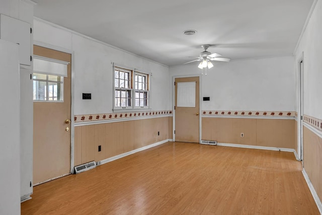 unfurnished room featuring ornamental molding, light wood-style flooring, and visible vents