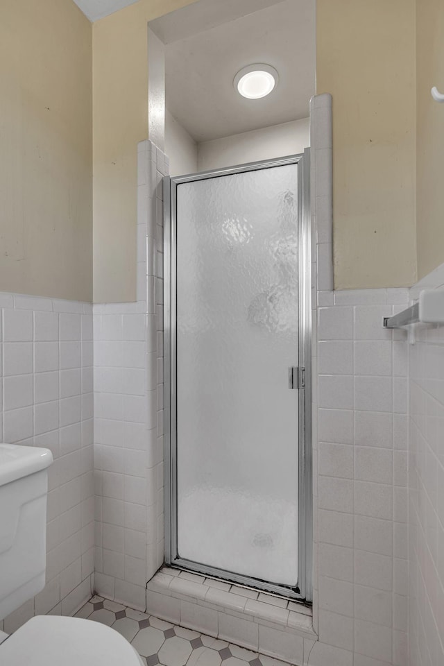 bathroom featuring toilet, tile walls, and a shower stall