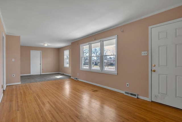 foyer entrance with crown molding, light wood-type flooring, visible vents, and baseboards