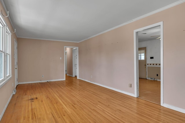 spare room featuring light wood finished floors, baseboards, and ornamental molding