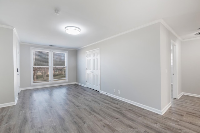 spare room with light wood-type flooring, crown molding, and baseboards