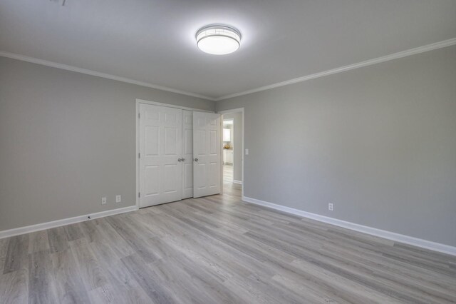 unfurnished bedroom with crown molding, light wood finished floors, and baseboards