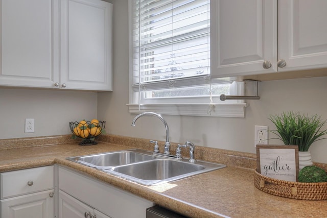 kitchen with white cabinetry, light countertops, and a sink