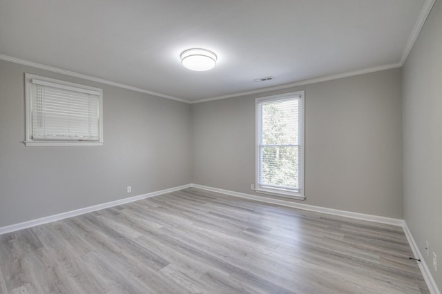 spare room featuring ornamental molding, light wood-style flooring, and visible vents