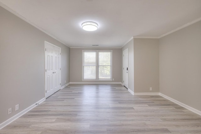 spare room with ornamental molding, light wood-style flooring, and baseboards