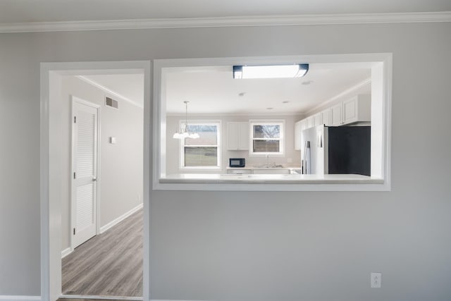 kitchen featuring visible vents, white cabinetry, light countertops, ornamental molding, and freestanding refrigerator