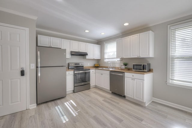 kitchen with light countertops, appliances with stainless steel finishes, white cabinets, a sink, and under cabinet range hood