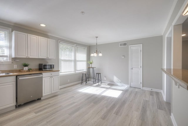 kitchen featuring visible vents, white cabinets, appliances with stainless steel finishes, ornamental molding, and hanging light fixtures