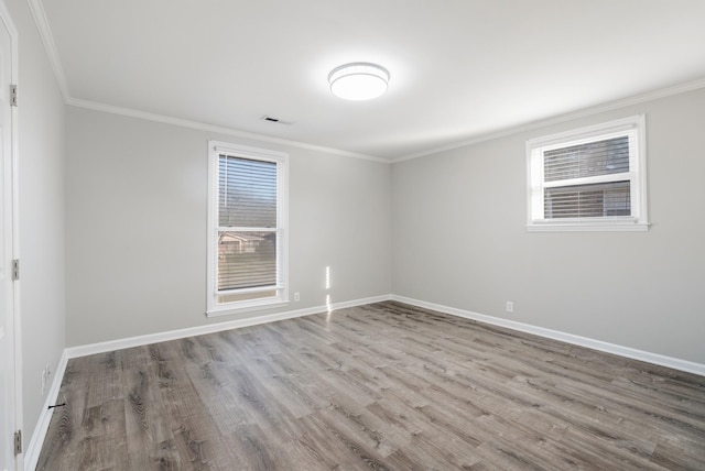 empty room with ornamental molding, wood finished floors, and baseboards