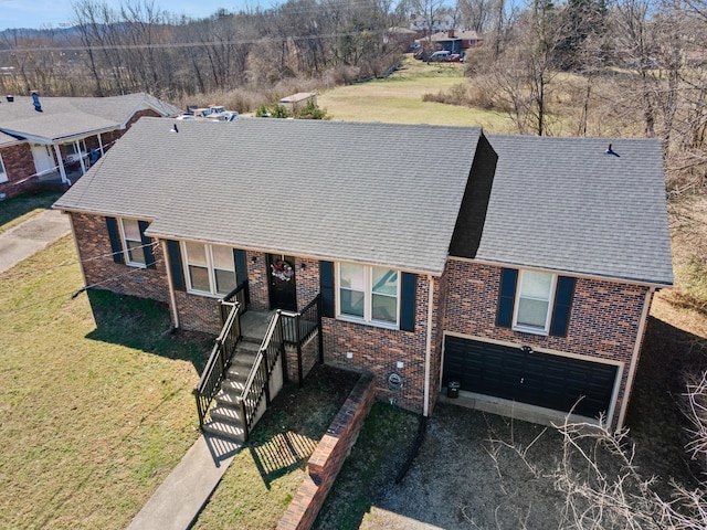 ranch-style house with a shingled roof, a front lawn, and brick siding