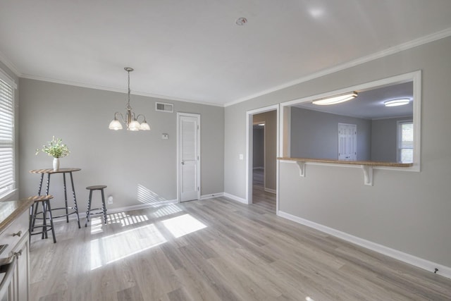 unfurnished room with ornamental molding, light wood-style flooring, visible vents, and baseboards