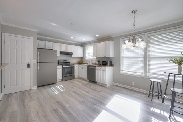 kitchen featuring white cabinets, under cabinet range hood, stainless steel appliances, and hanging light fixtures