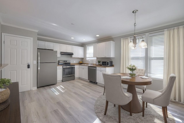 kitchen with stainless steel appliances, under cabinet range hood, white cabinetry, and pendant lighting