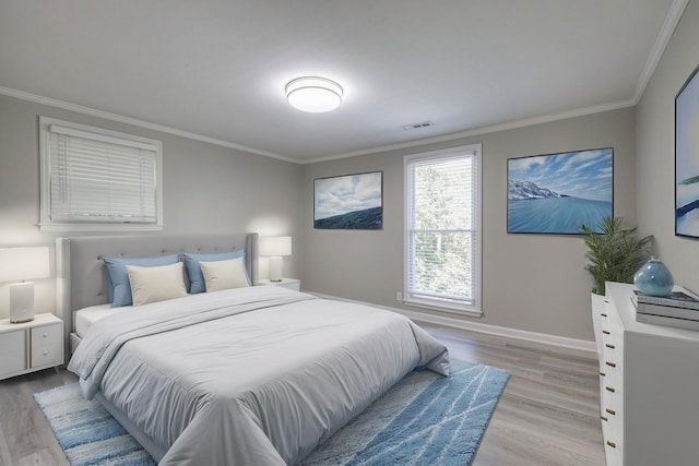 bedroom featuring light wood-style floors, visible vents, and crown molding