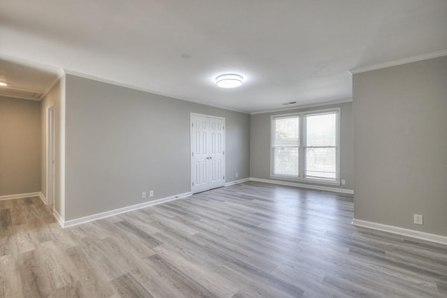 empty room with ornamental molding, light wood finished floors, and baseboards