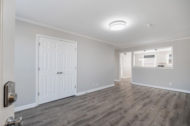 interior space featuring ornamental molding, dark wood-style flooring, and baseboards