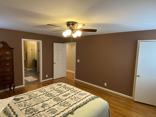 bedroom featuring ceiling fan, ensuite bath, baseboards, and wood finished floors