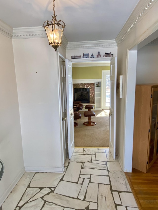 hall featuring a chandelier, light wood-style floors, baseboards, and crown molding